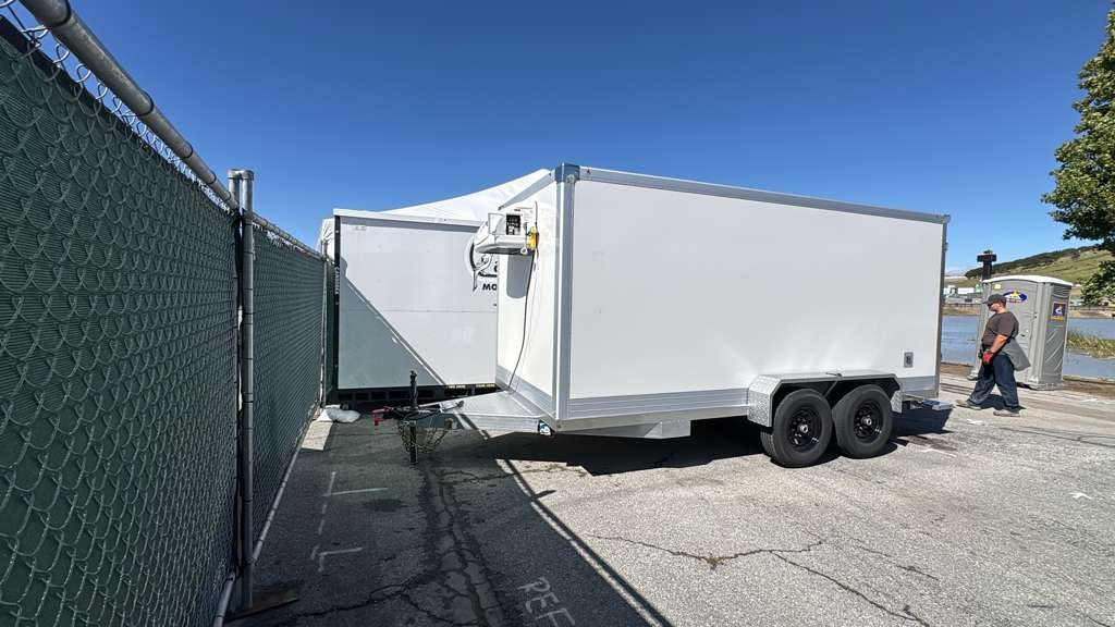 White KryoFridge refrigerated trailer staged on asphalt behind a commercial lot