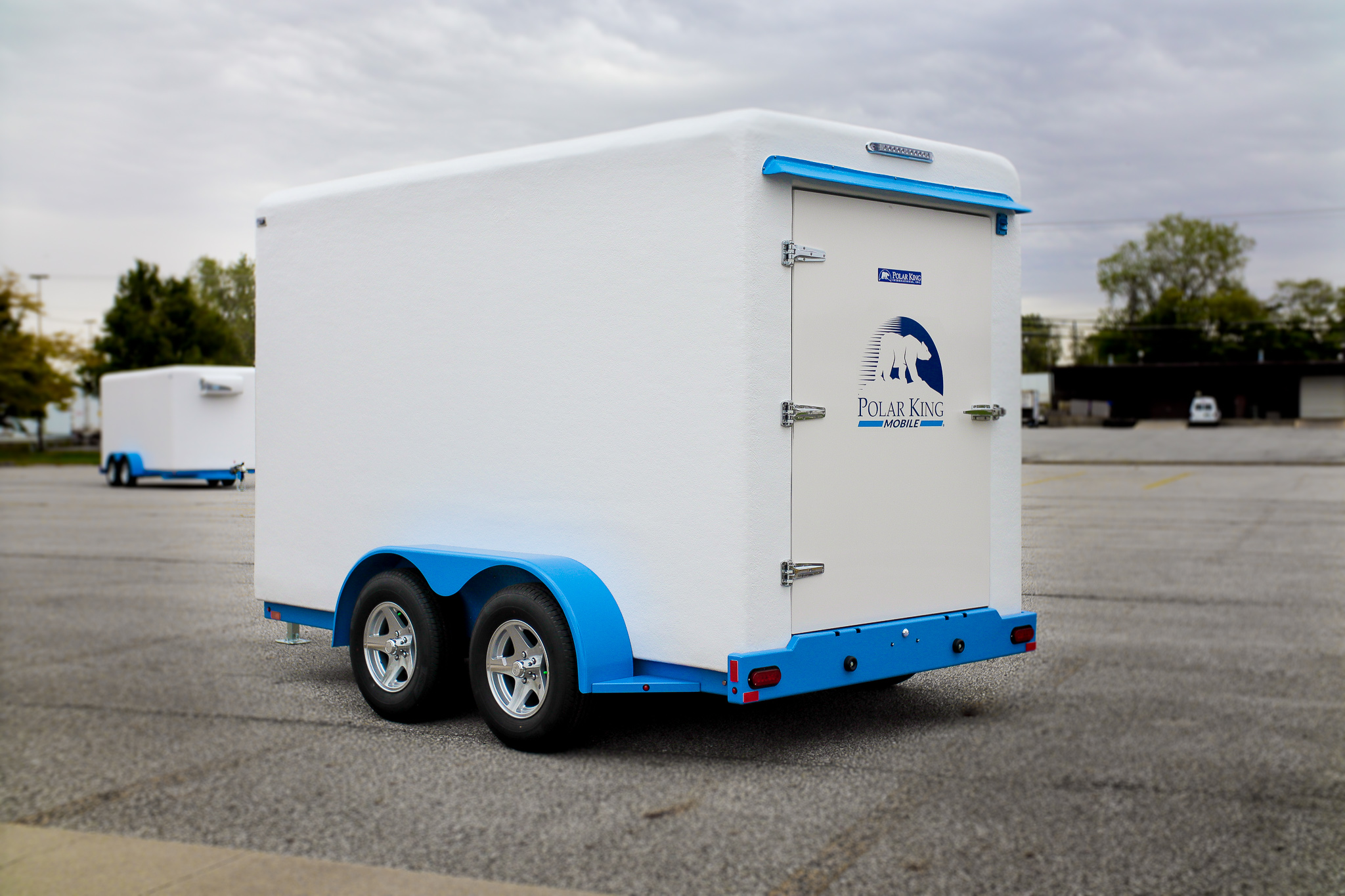 Clean white-and-blue KryoFridge freezer trailer, side profile, parked in an open lot