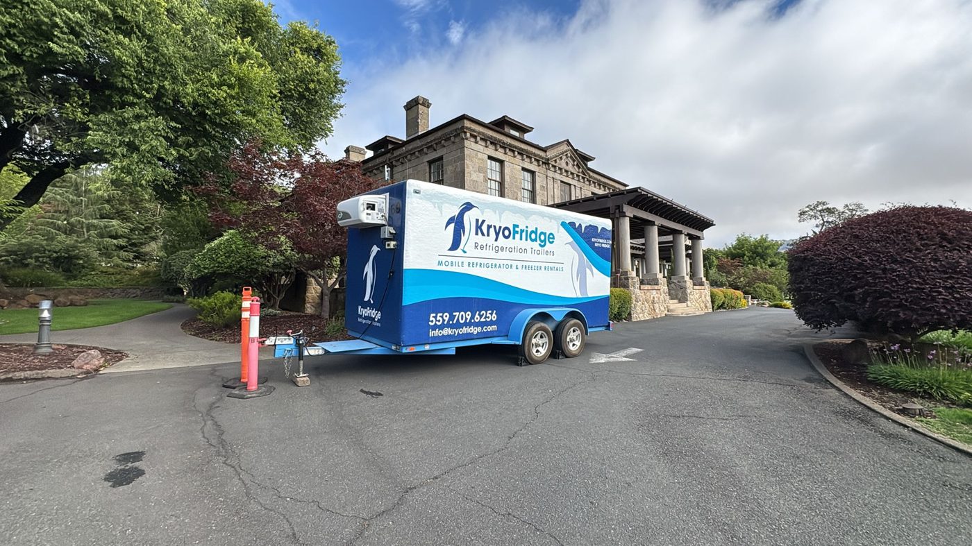 KryoFridge-branded blue and white refrigeration trailer being hauled to a Mesa job site, owner-operated and ready to deliver