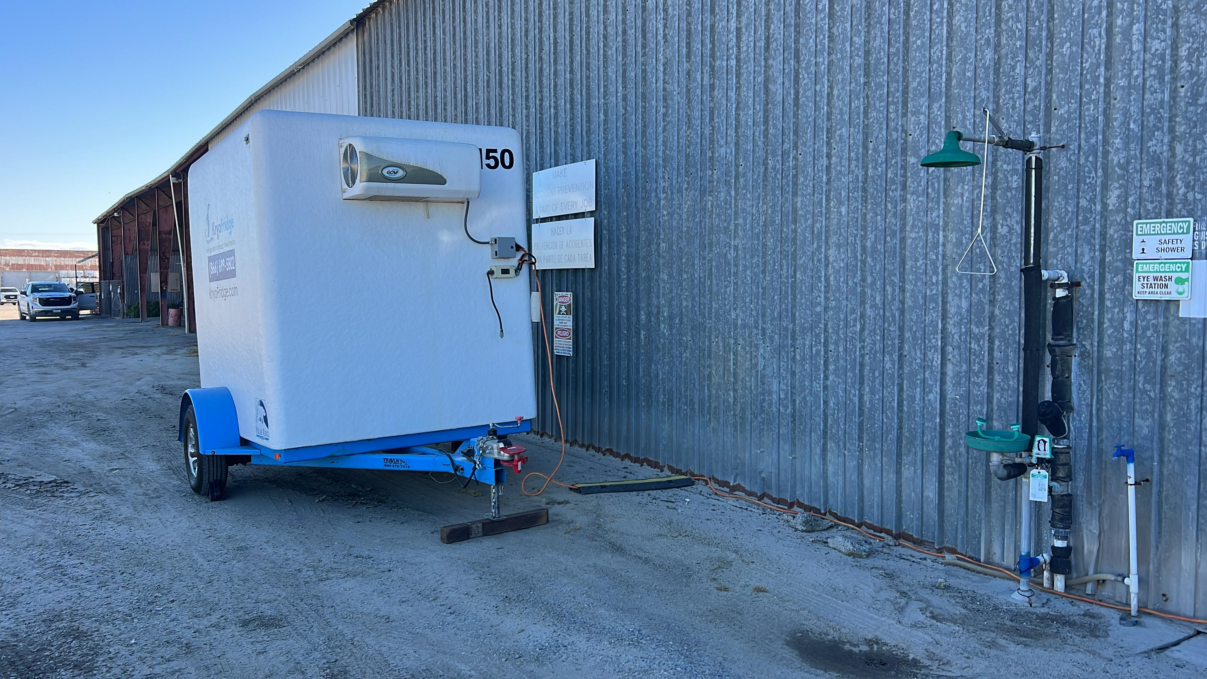 KryoFridge refrigerated trailer with a top-mounted reefer unit positioned against a commercial building