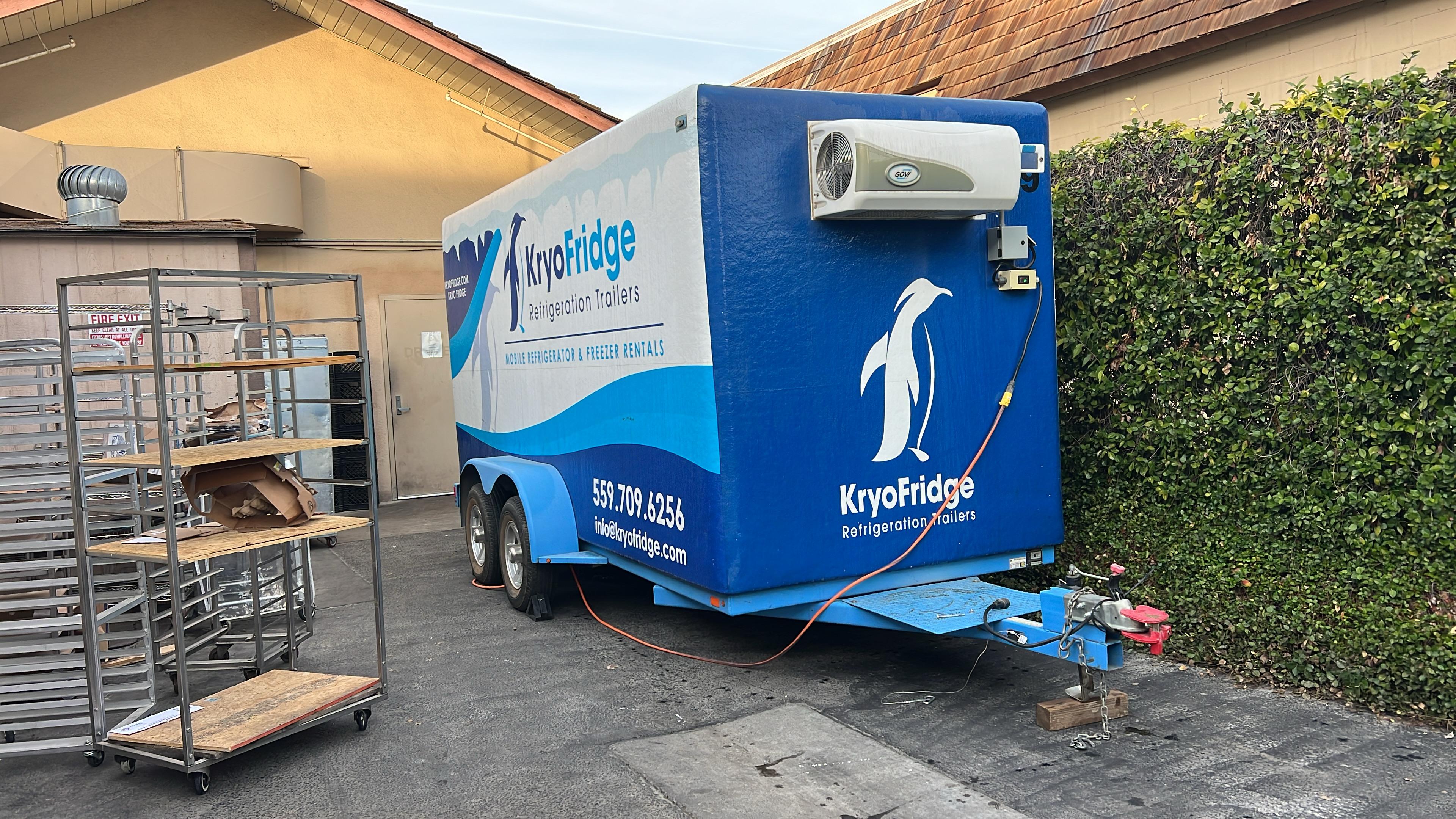 Blue KryoFridge-branded refrigeration trailer with the penguin logo, parked and powered for a Tucson cold-storage job