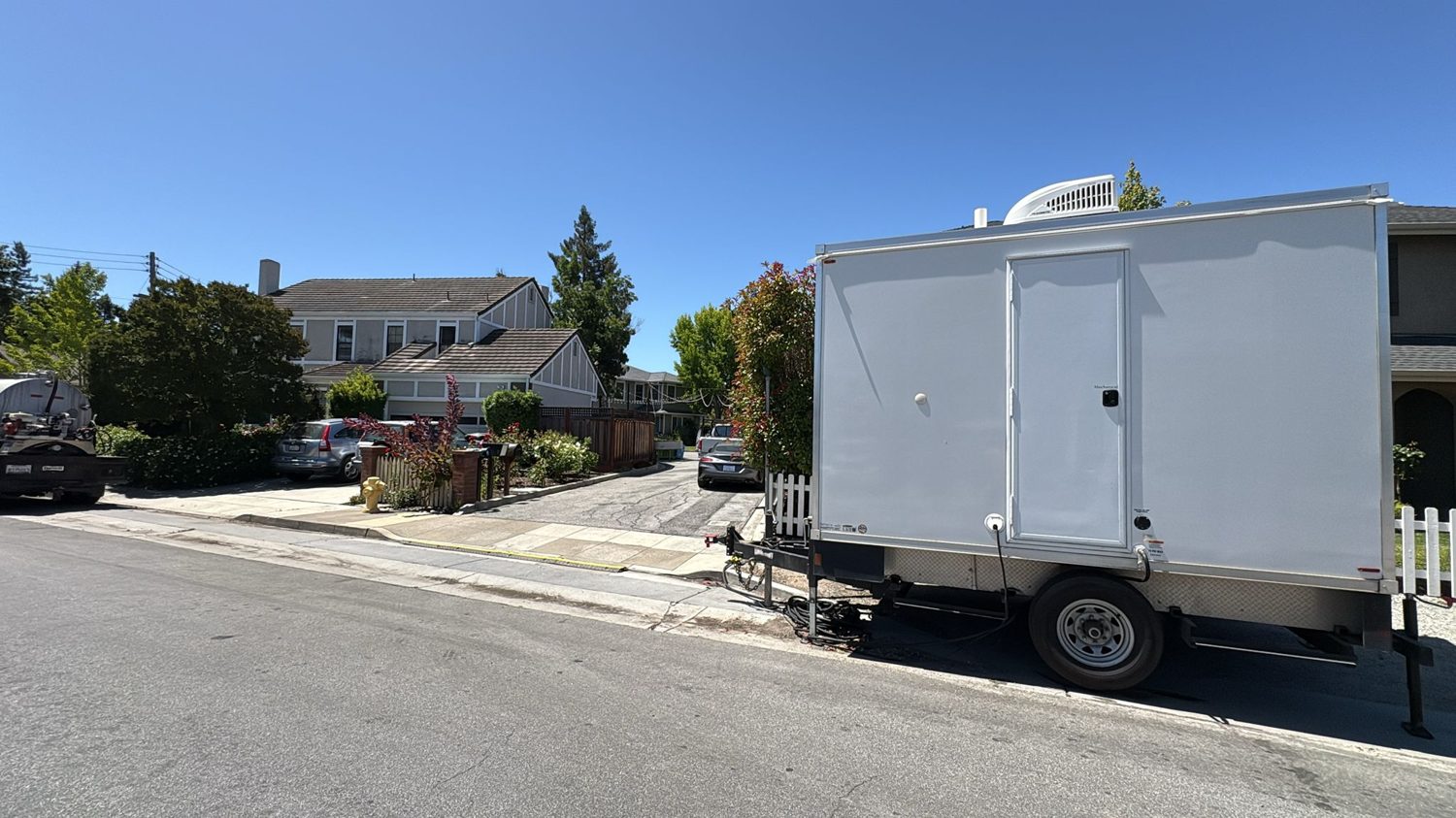 Clean white KryoFridge freezer trailer photographed in side profile on a Fullerton residential street, rooftop refrigeration unit visible, ready for delivery