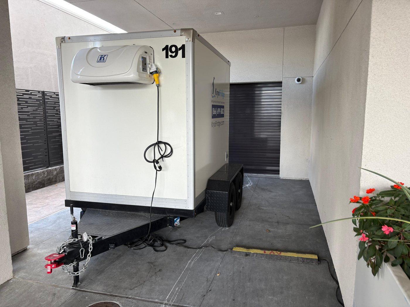 KryoFridge reefer trailer with its refrigeration unit parked tight against a commercial building