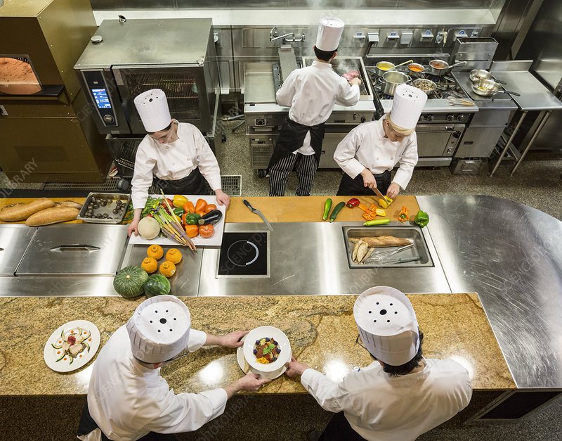 Busy Visalia commercial restaurant kitchen line with cooks plating during a downtown dinner service