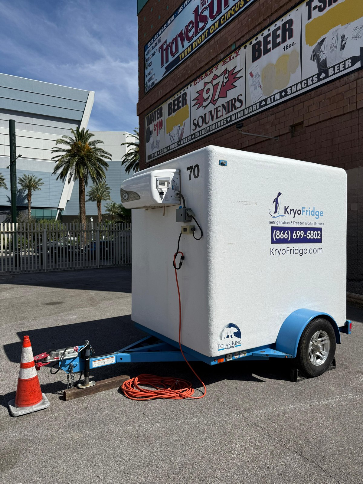 KryoFridge 16 foot freezer trailer parked behind a quick-service restaurant kitchen door on a sunny Tracy afternoon