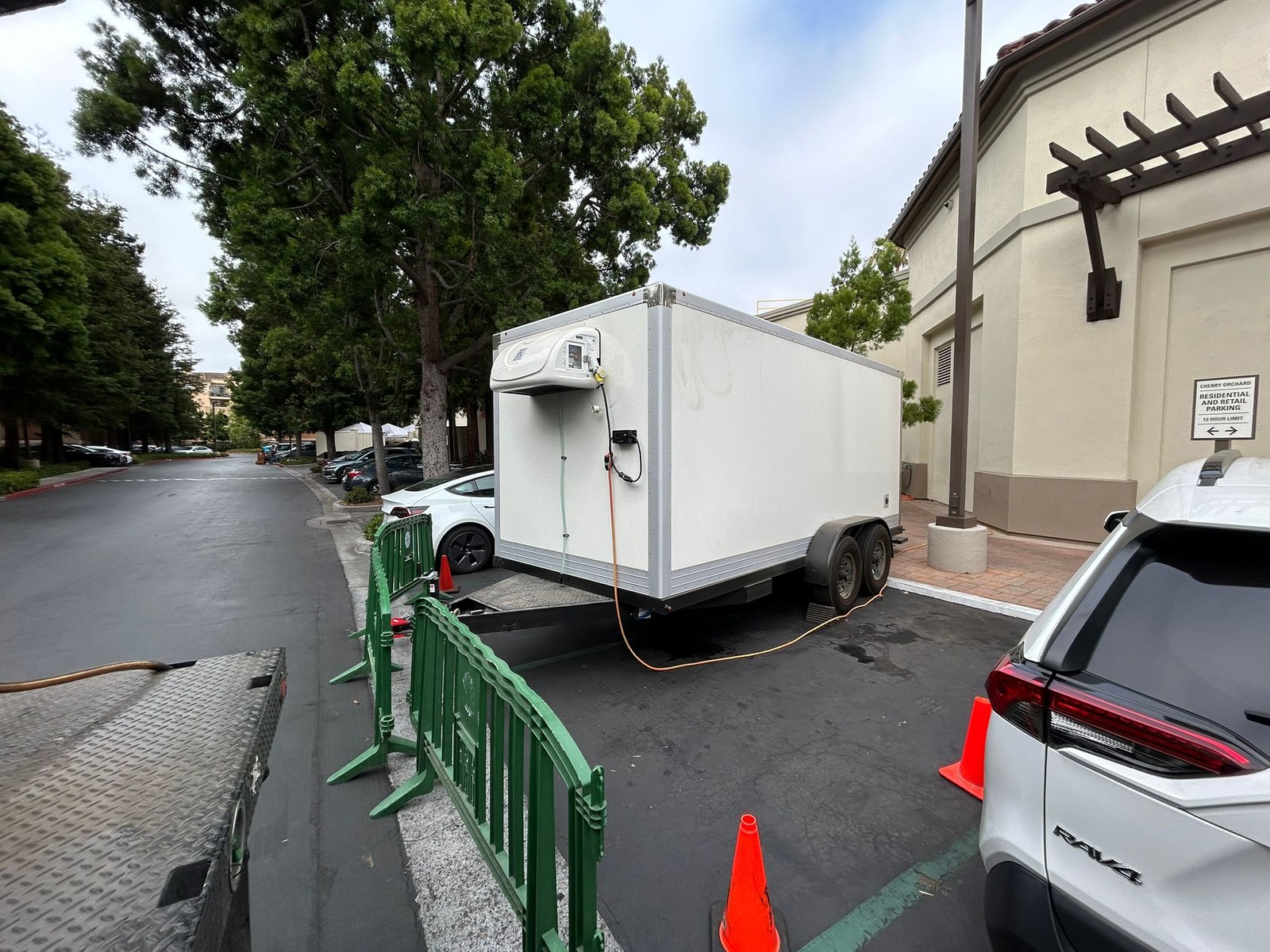 Plain white KryoFridge refrigerated trailer parked discreetly in a quiet rear service lot beside a low building