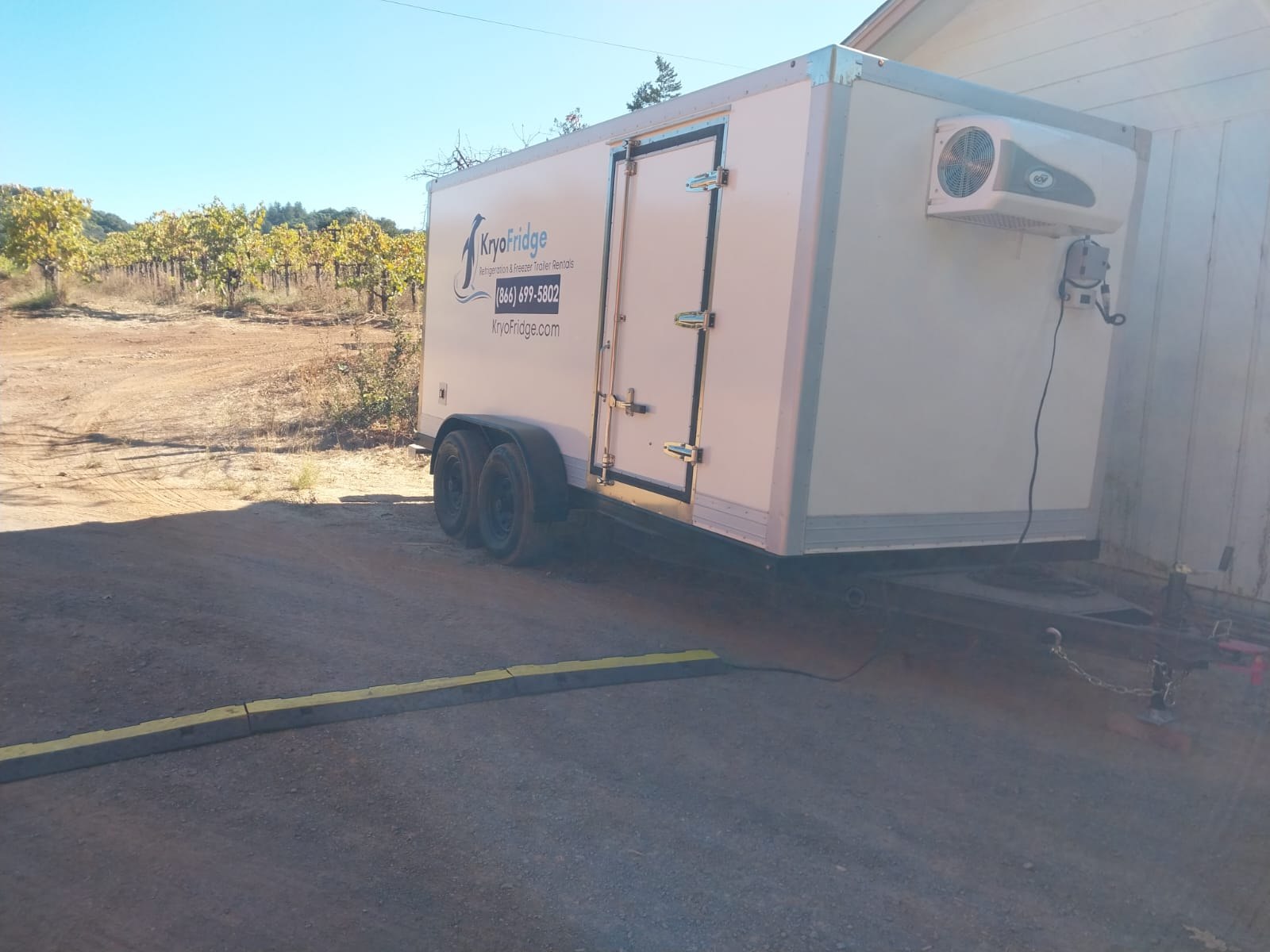 KryoFridge cold storage trailer backed up to the loading dock of a small flex warehouse building