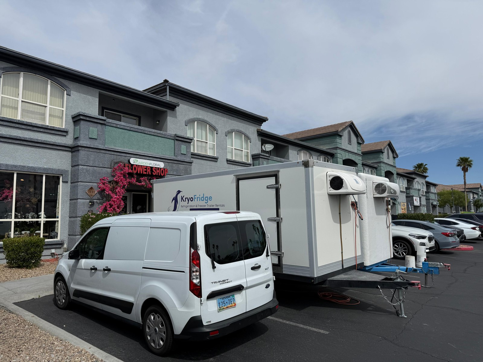 KryoFridge 6x12 cooler trailer parked behind a Midland flower shop while staff carry buckets of roses inside