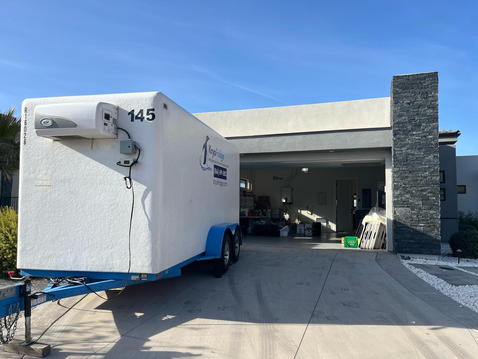 a freezer trailer at a warehouse dock near a container port with trucks nearby