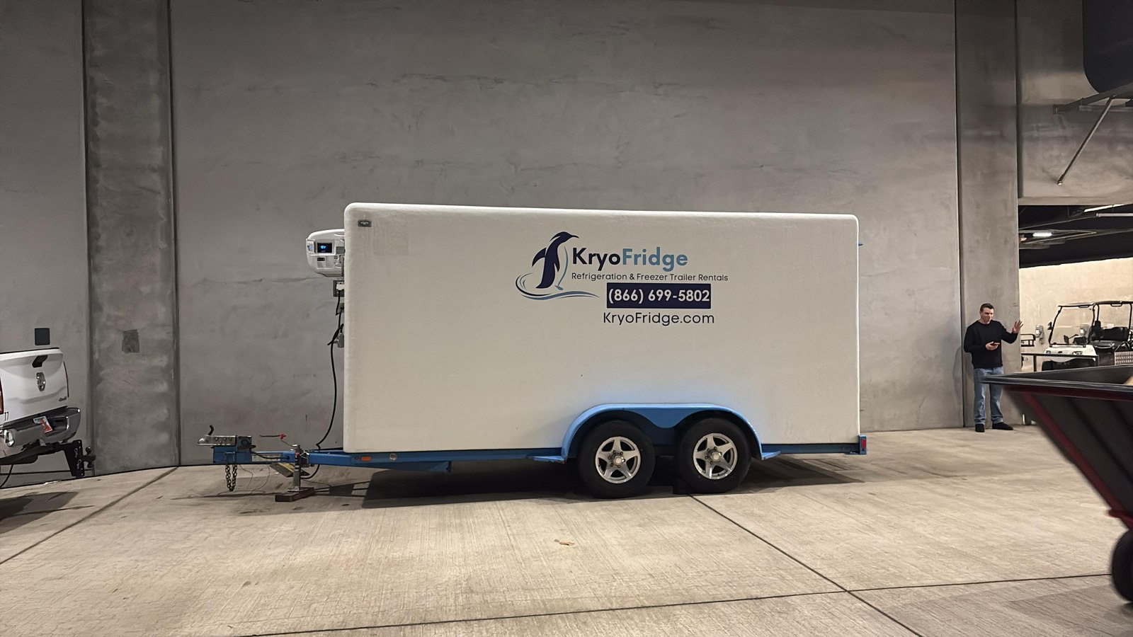 a KryoFridge freezer trailer parked behind a restaurant with kitchen staff loading product
