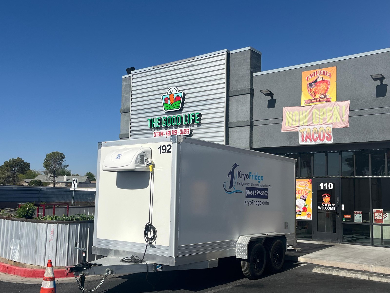 a refrigerated trailer next to a medical building loading area on a sunny morning